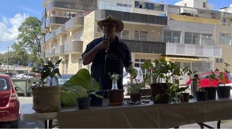 A man stands at a market stall, speaking into a microphone 