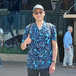A man in a blue shirt gives a thumbs up