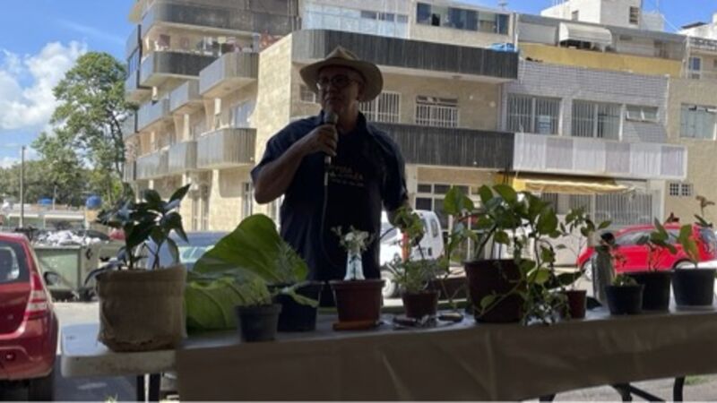 A man stands at a market stall, speaking into a microphone 