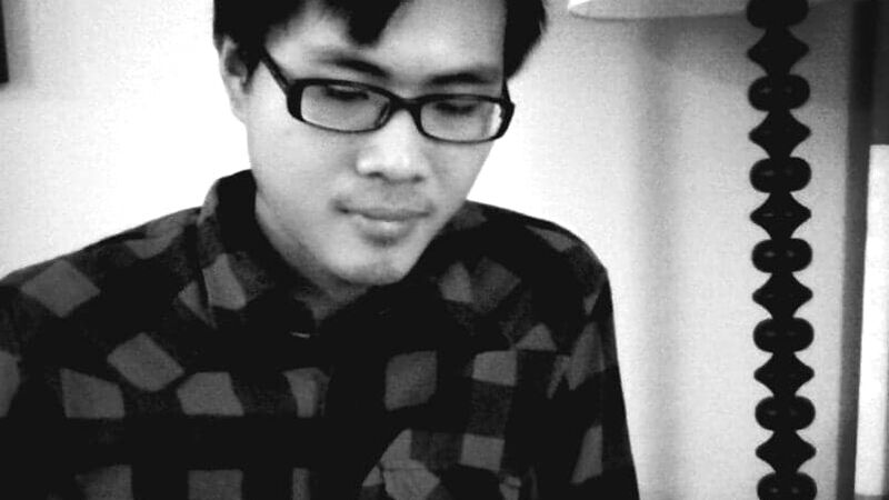 A black and white photo of Leo Chu reading a book