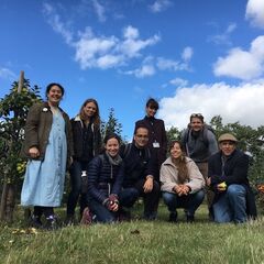 A group photo of 8 people standing in an apple orchard against a blue sky