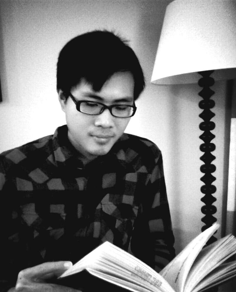 A black and white photo of Leo Chu reading a book